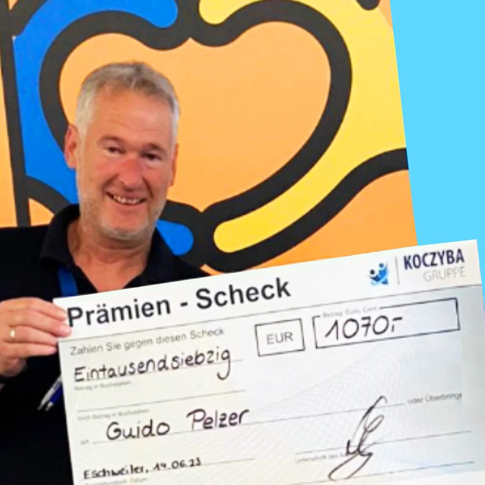 Guido Pelzer hält einen Prämienscheck der Koczyba Gruppe über 1.070 Euro in die Kamera, Symbolbild für Anerkennung, Wertschätzung und Prämienkultur im Unternehmen.