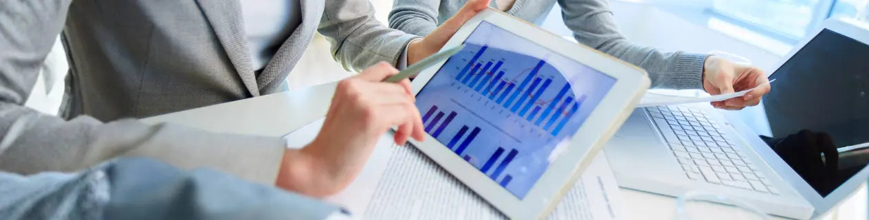 Foto zur Identifikation mit Leistungen und Ergebnissen im Unternehmen, Team analysiert Kennzahlen auf dem Tablet und steht für datenbasierte Entscheidungen, Verantwortung und wirtschaftlichen Erfolg.