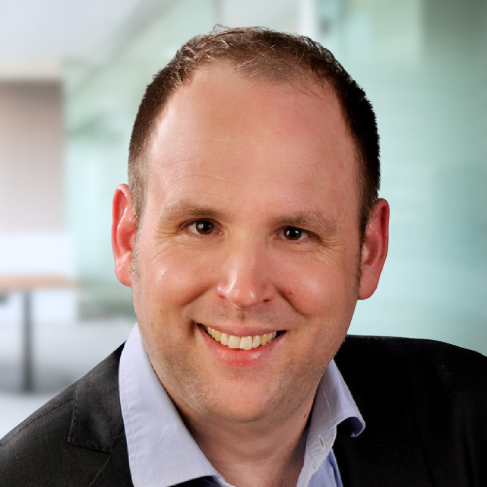 Porträt von J. Eggerath, Prokurist, im Business Outfit vor modernem Hintergrund.