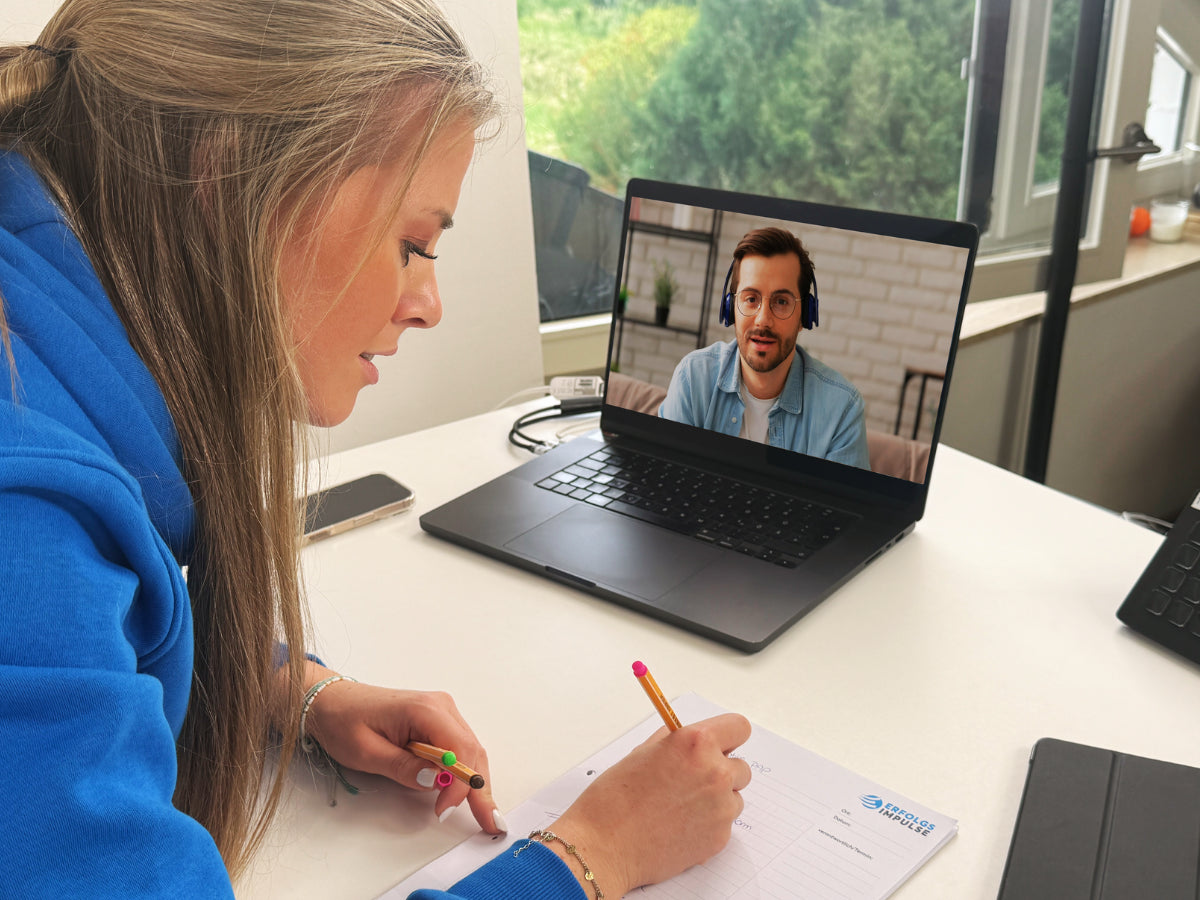 Alina Klejbor im Zoom Call mit einem Teilnehmer am Laptop, macht Notizen am Schreibtisch, digitale Beratung und Online Coaching der Erfolgsimpulse GmbH.