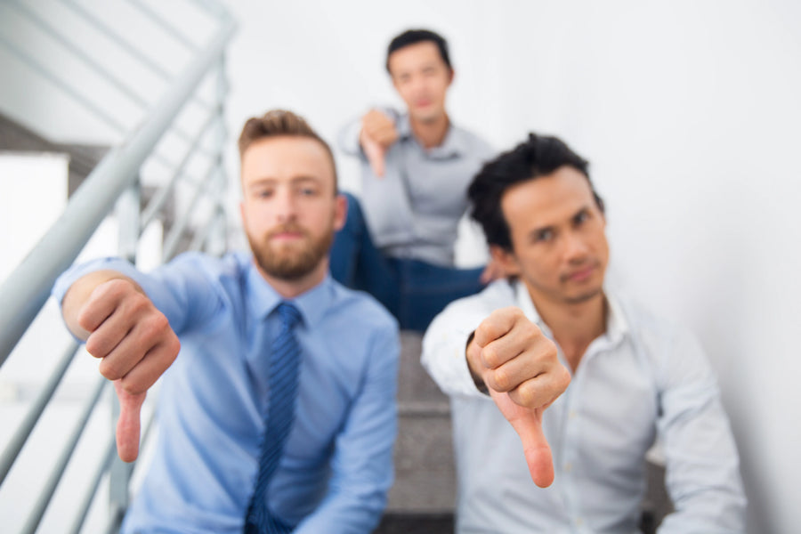 Stockfoto mit unzufriedenen Mitarbeitern im Unternehmen, Team zeigt Ablehnung und steht sinnbildlich für fehlende Wertschätzung, geringe Motivation und schwache Unternehmenskultur.