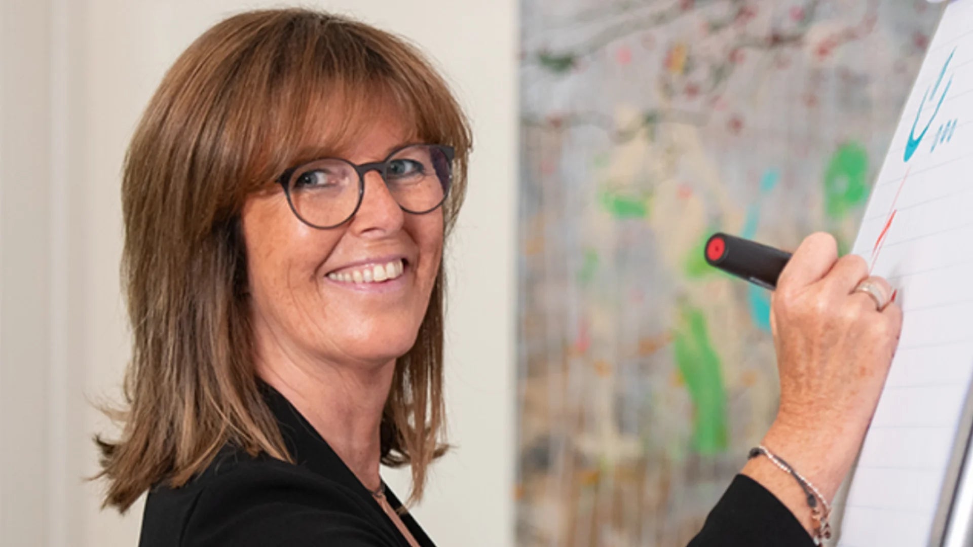 Porträt von Sabine Klejbor mit Brille beim Schreiben auf einem Flipchart, als Business Motiv für Coaching, Training, Persönlichkeitsentwicklung, Führung und professionelle Seminarbegleitung.